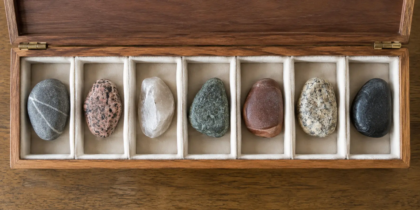 Seven stones stored separately in seven padded compartments of an open wooden box.