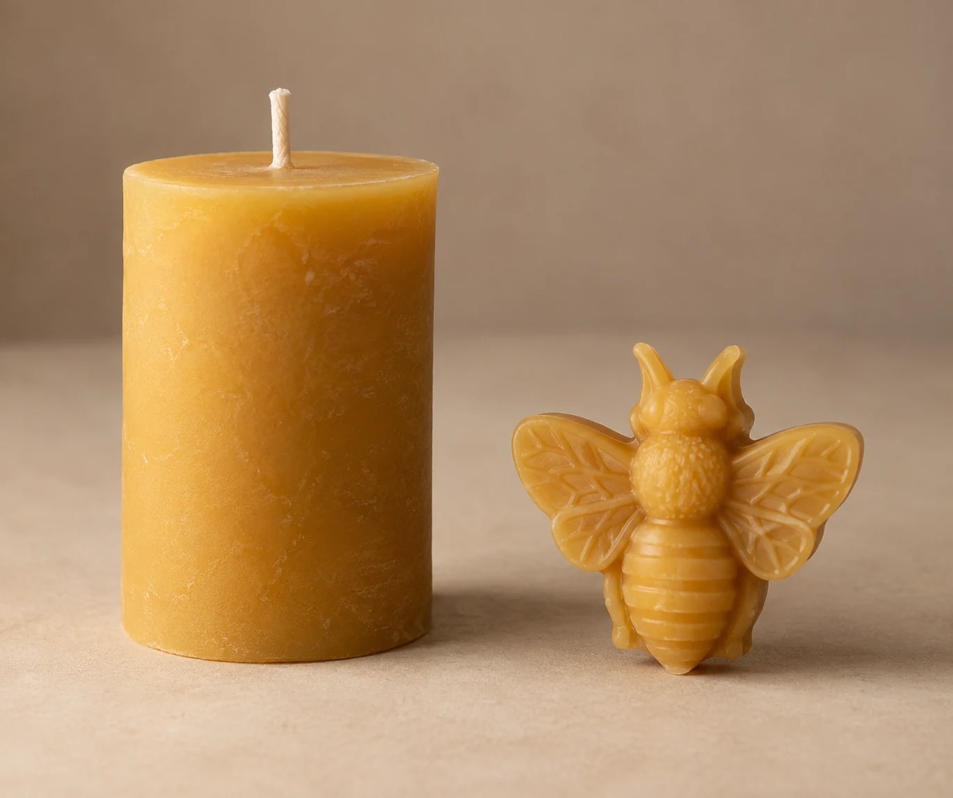 An unlit wax candle beside a small molded wax ornament.