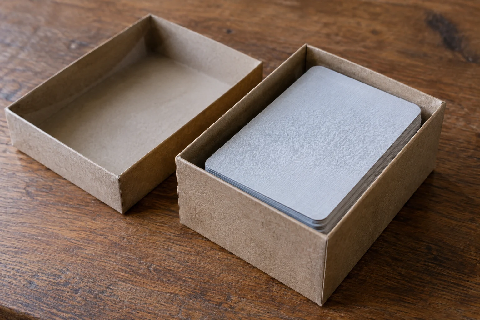 A stack of cards inside an open cardboard box, with the lid set beside it.