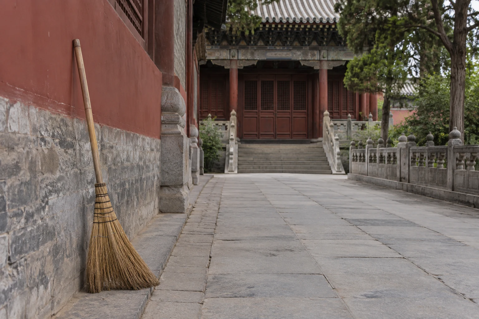 Broom beside a clear walkway outside a temple building.