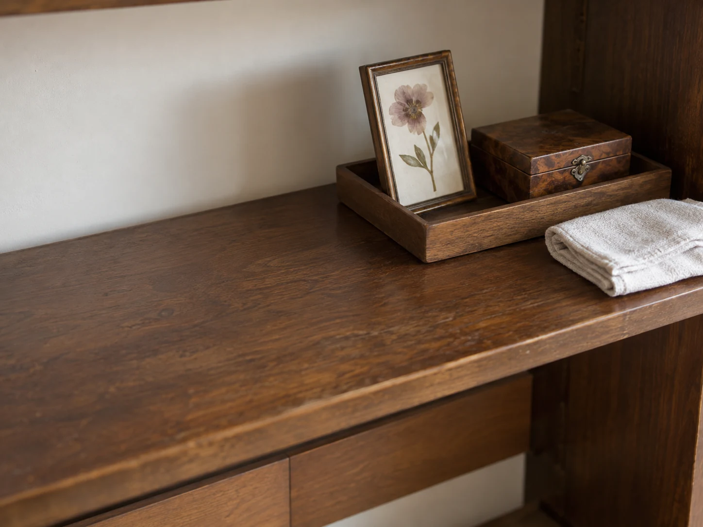 Cleared remembrance shelf with keepsakes on a tray and a folded dusting cloth nearby.