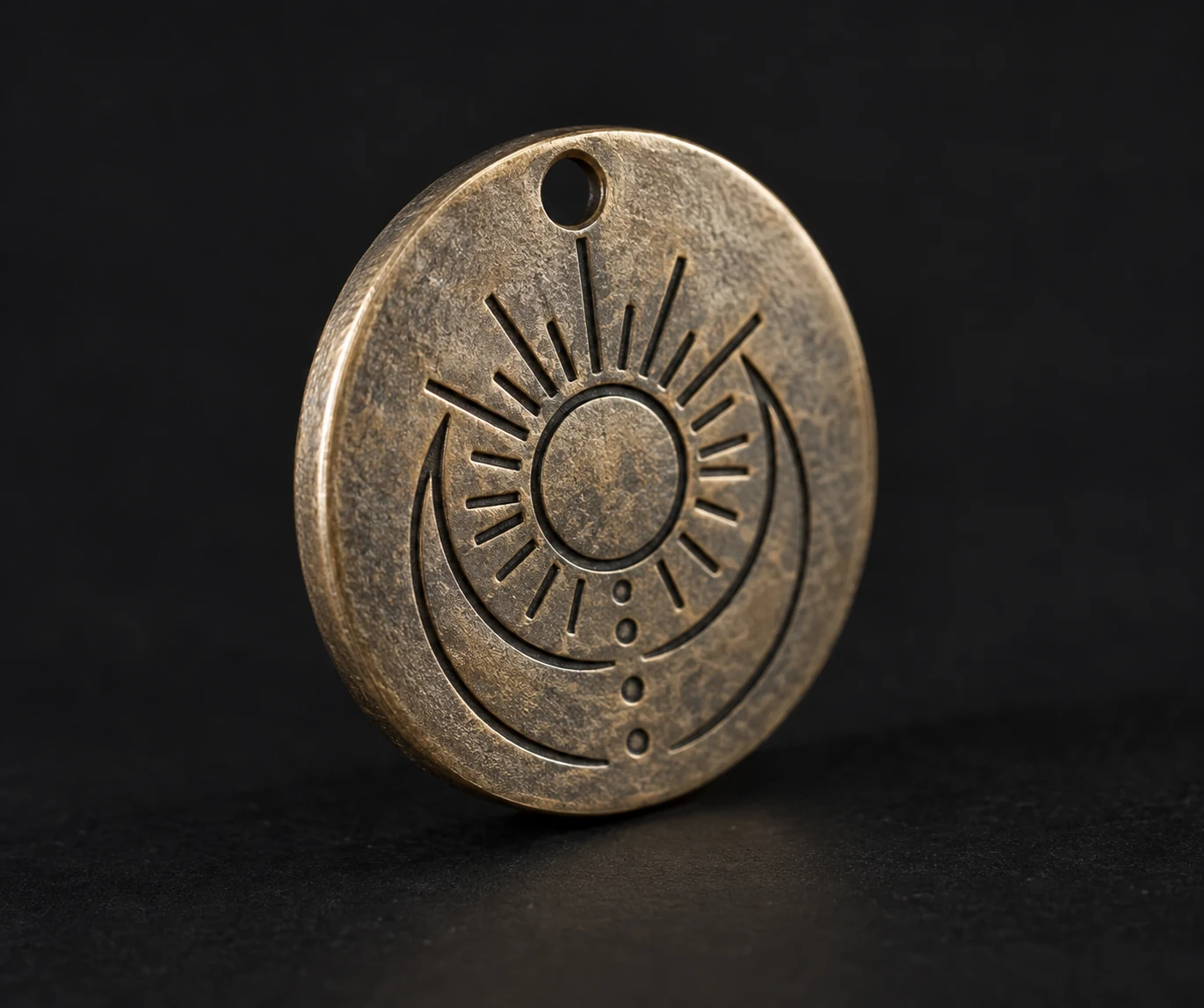 Round metal pendant with a small suspension hole and geometric engraving.