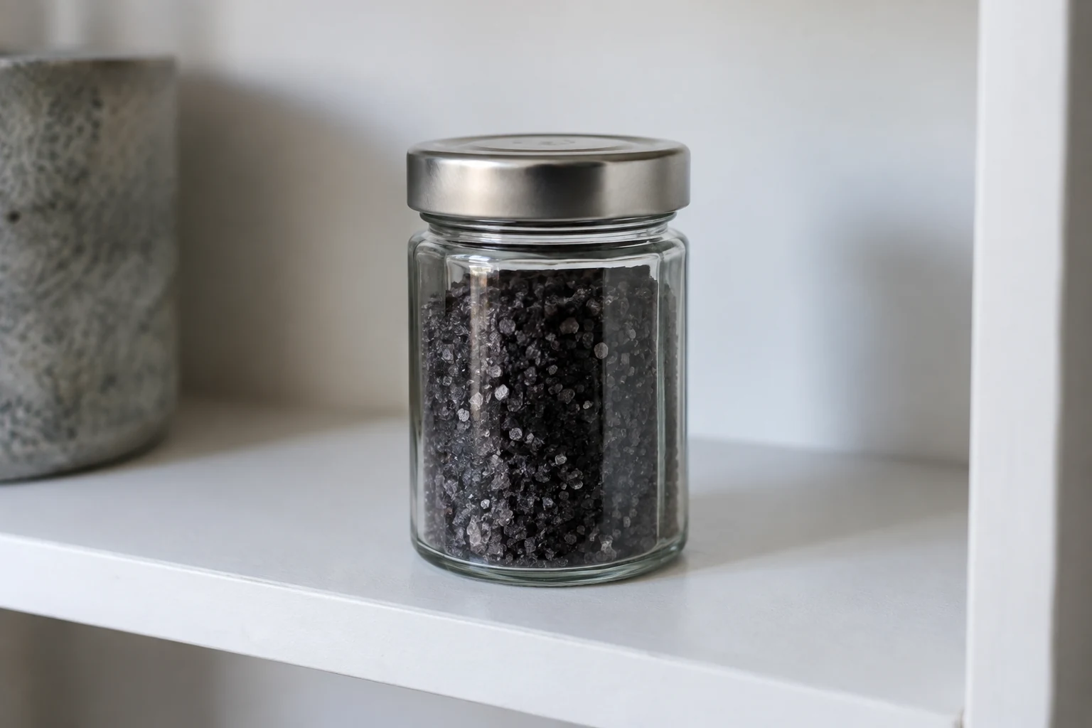 Closed glass jar containing a dark granular blend on a home shelf.