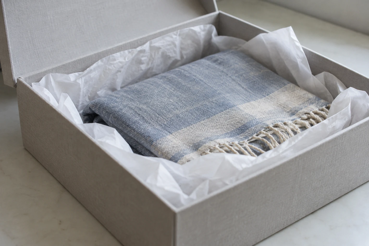 A folded cloth cushioned with tissue inside an open storage box.