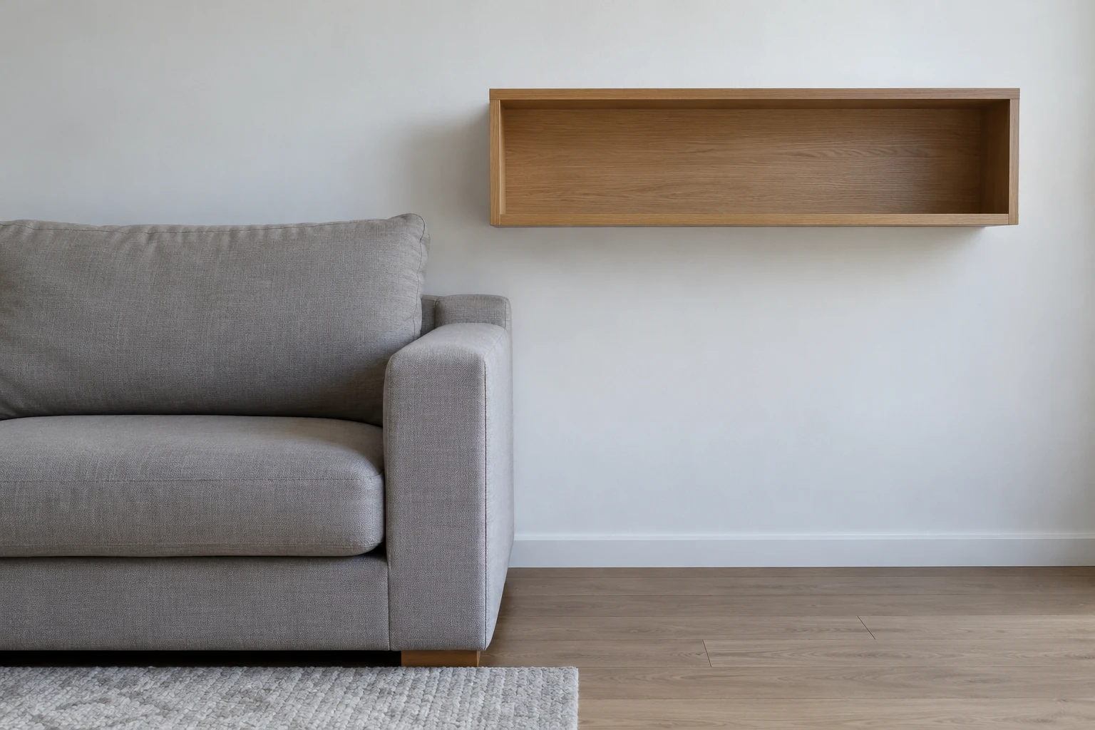 Empty wall shelf above and beside a sofa arm, with a clear gap between them.
