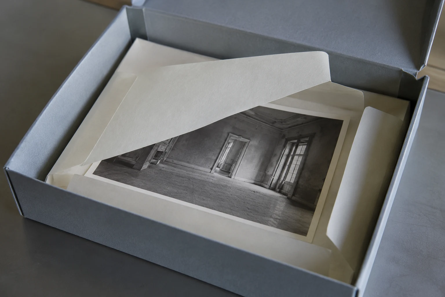 A photograph of an empty building lies inside an open paper enclosure in a storage box.